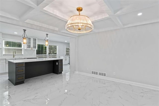 kitchen featuring visible vents, baseboards, coffered ceiling, and light countertops