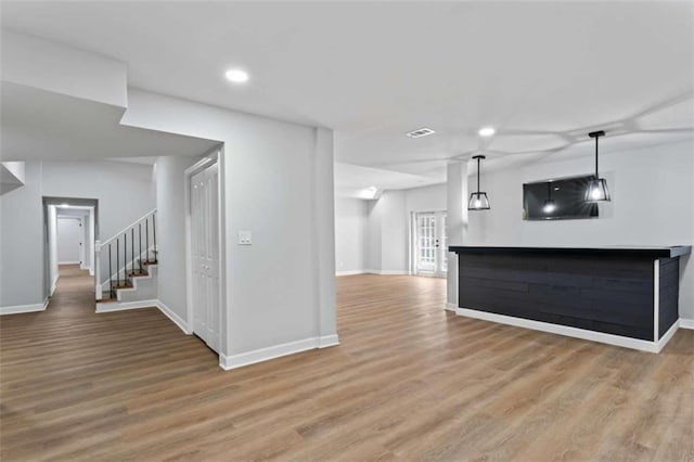 unfurnished living room featuring recessed lighting, light wood-type flooring, stairs, and baseboards