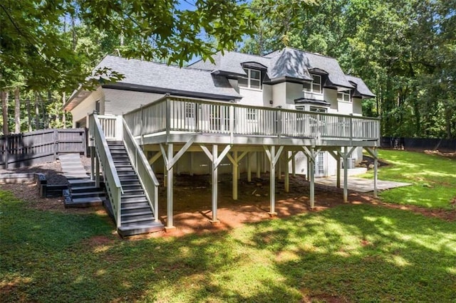 rear view of house with fence, roof with shingles, stairs, a deck, and a lawn