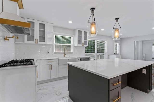 kitchen featuring a center island, stainless steel gas stovetop, custom exhaust hood, marble finish floor, and a sink