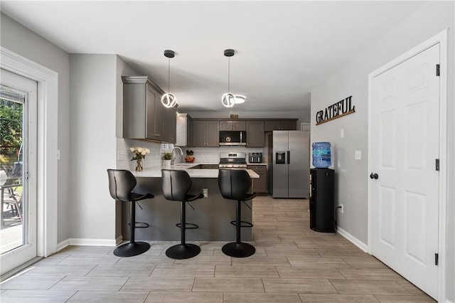 4901 Wilkie Way NW, Acworth, GA 30102 - kitchen featuring stainless steel appliances, wood tiled floors, a peninsula, a kitchen breakfast bar, and light countertops