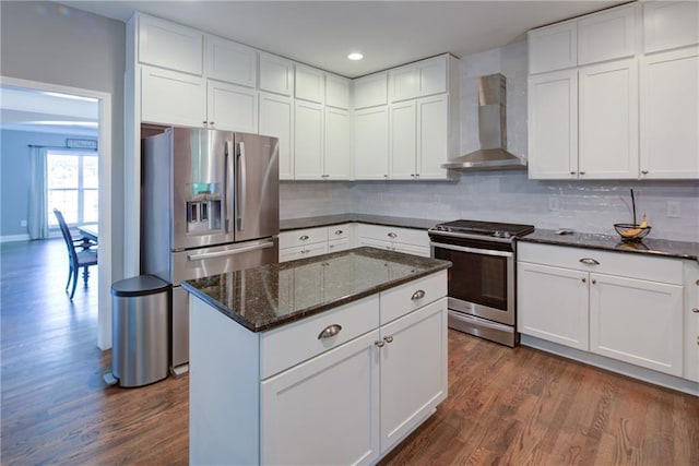 kitchen with appliances with stainless steel finishes, wall chimney exhaust hood, dark wood finished floors, backsplash, and recessed lighting