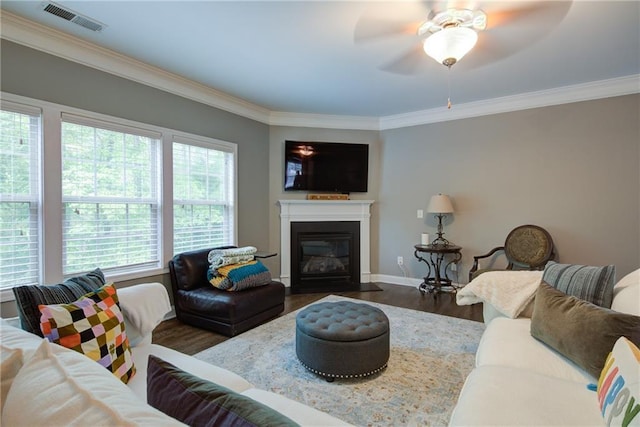 living area with ornamental molding, a ceiling fan, wood finished floors, a fireplace with flush hearth, and baseboards