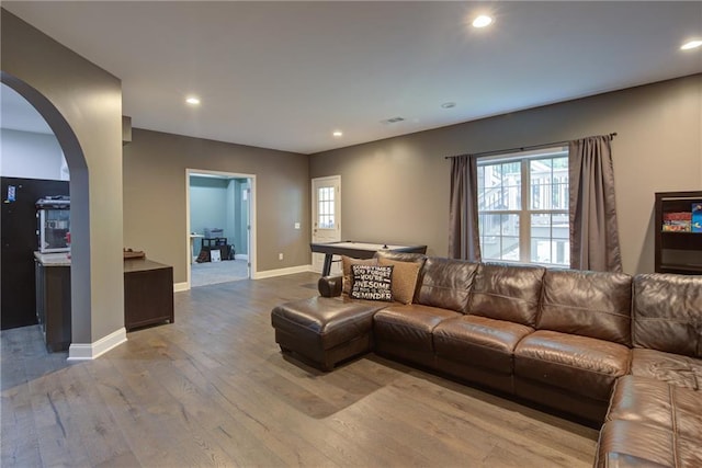 living room featuring arched walkways, hardwood / wood-style floors, recessed lighting, and baseboards