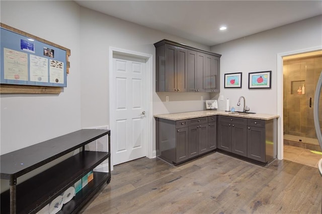 kitchen featuring a sink, dark wood-type flooring, recessed lighting, light stone countertops, and gray cabinets