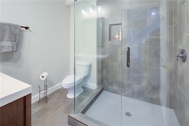 bathroom with toilet, a stall shower, vanity, baseboards, and tile patterned floors