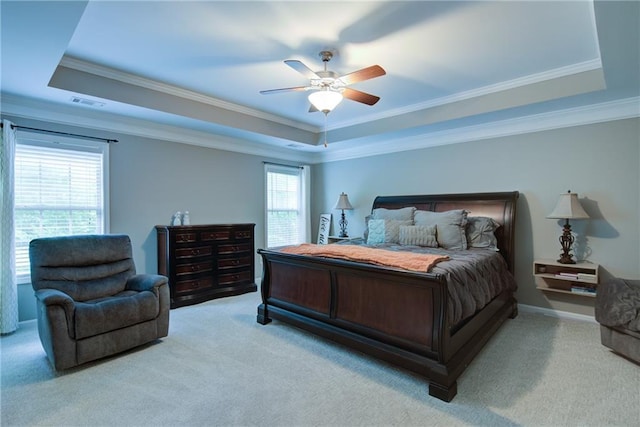 bedroom with a raised ceiling, light colored carpet, crown molding, and a ceiling fan