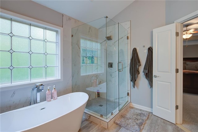full bathroom featuring a marble finish shower, a freestanding bath, wood finished floors, and lofted ceiling