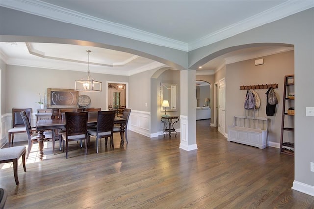 dining space with dark wood-style floors, arched walkways, a tray ceiling, and crown molding