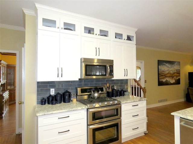 kitchen with white cabinetry, crown molding, stainless steel appliances, and decorative backsplash