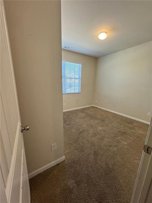 unfurnished room featuring visible vents, dark carpet, and baseboards