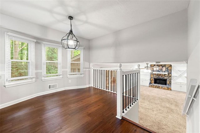 interior space featuring wood finished floors, a ceiling fan, a stone fireplace, and baseboards