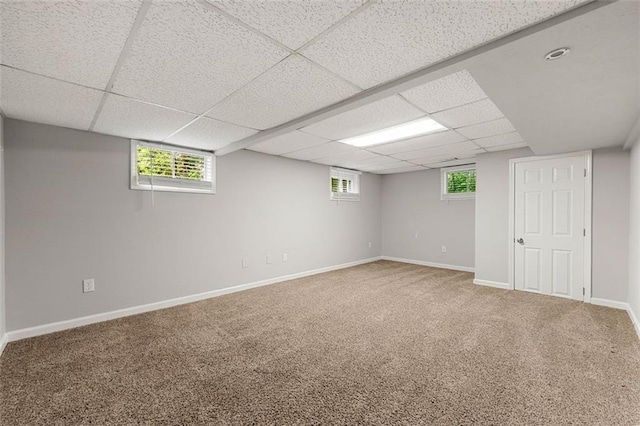 below grade area with a paneled ceiling, carpet, and baseboards
