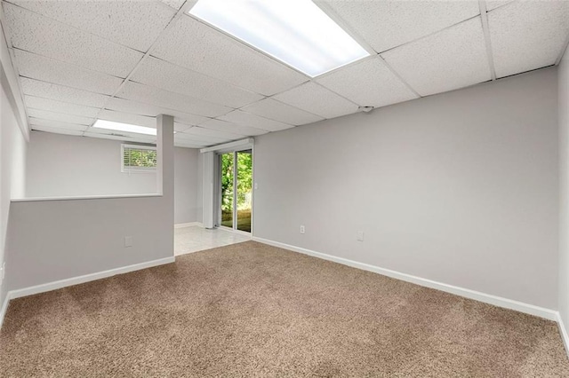 spare room with carpet, a paneled ceiling, and baseboards