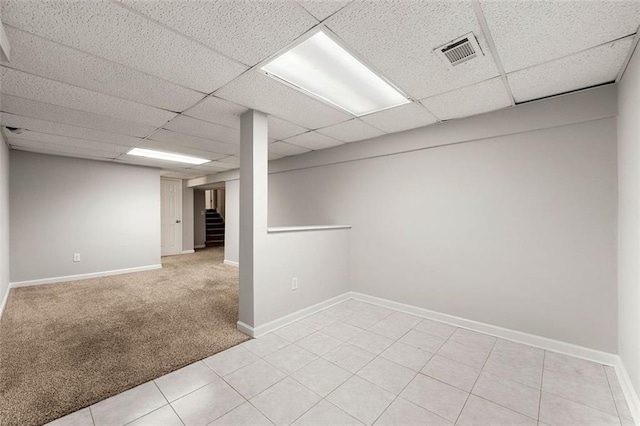 spare room featuring a paneled ceiling, stairs, baseboards, and light colored carpet