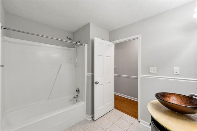 bathroom featuring tile patterned flooring,  shower combination, vanity, and baseboards
