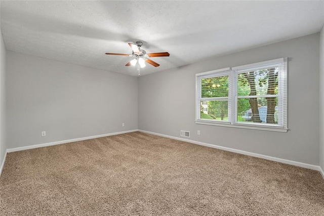 carpeted spare room with a ceiling fan and baseboards