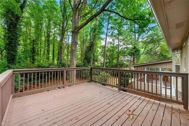 wooden terrace featuring view of wooded area
