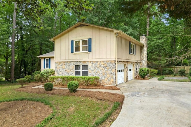 view of side of home featuring a chimney, stone siding, driveway, a garage, and board and batten siding