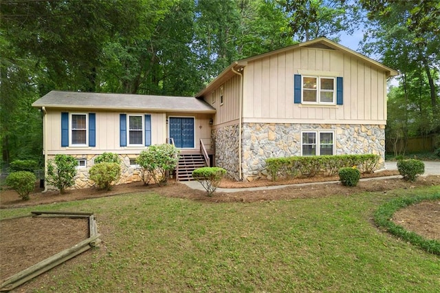 tri-level home featuring stone siding, board and batten siding, and a front lawn