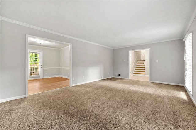 carpeted empty room featuring stairway, crown molding, and baseboards