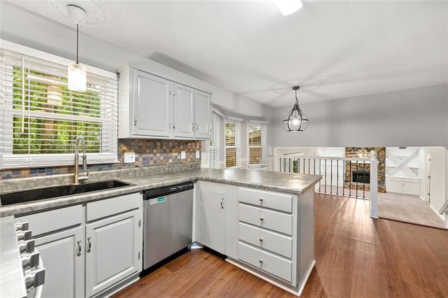 kitchen with dishwasher, a sink, a peninsula, white cabinetry, and dark wood finished floors
