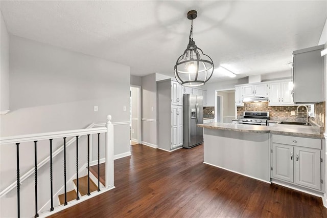 kitchen with stainless steel appliances, under cabinet range hood, a peninsula, a sink, and decorative backsplash