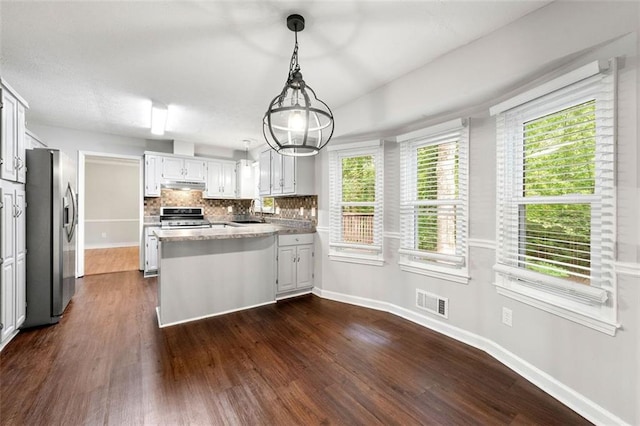 kitchen featuring stainless steel appliances, a peninsula, dark wood finished floors, and under cabinet range hood