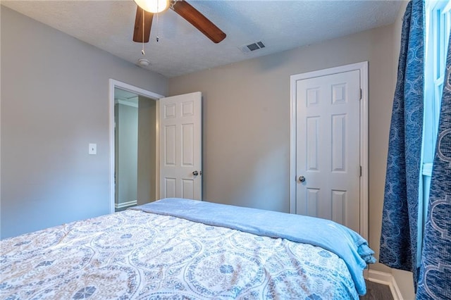 bedroom featuring ceiling fan, visible vents, and a textured ceiling