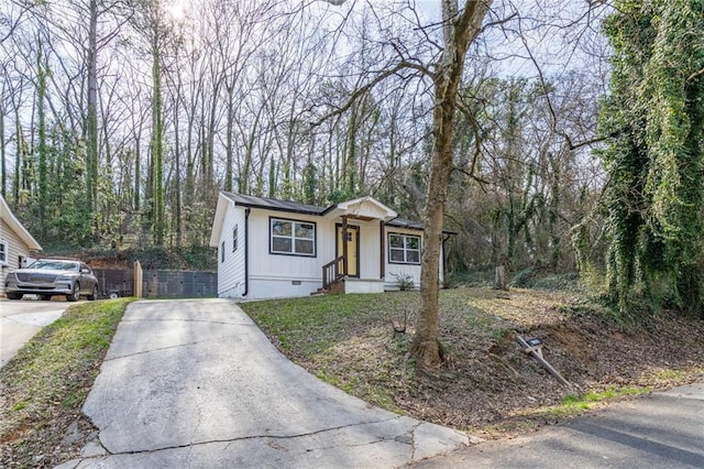 view of front of property with crawl space, board and batten siding, fence, and concrete driveway