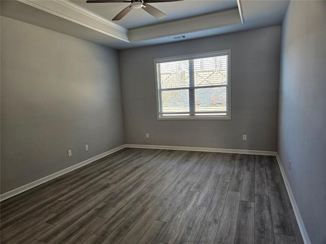 unfurnished room with dark wood-type flooring, a tray ceiling, visible vents, and baseboards