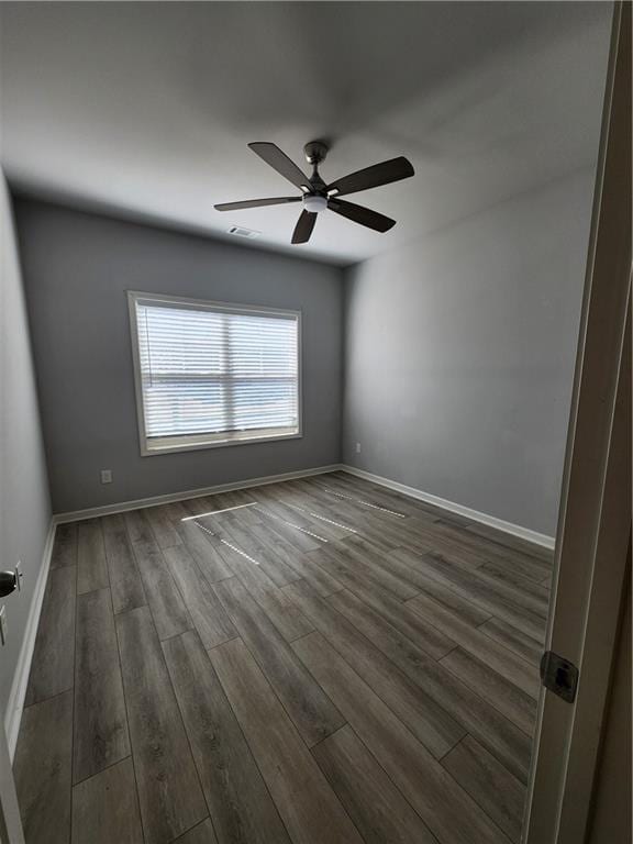 unfurnished room featuring baseboards, visible vents, ceiling fan, and dark wood-style flooring