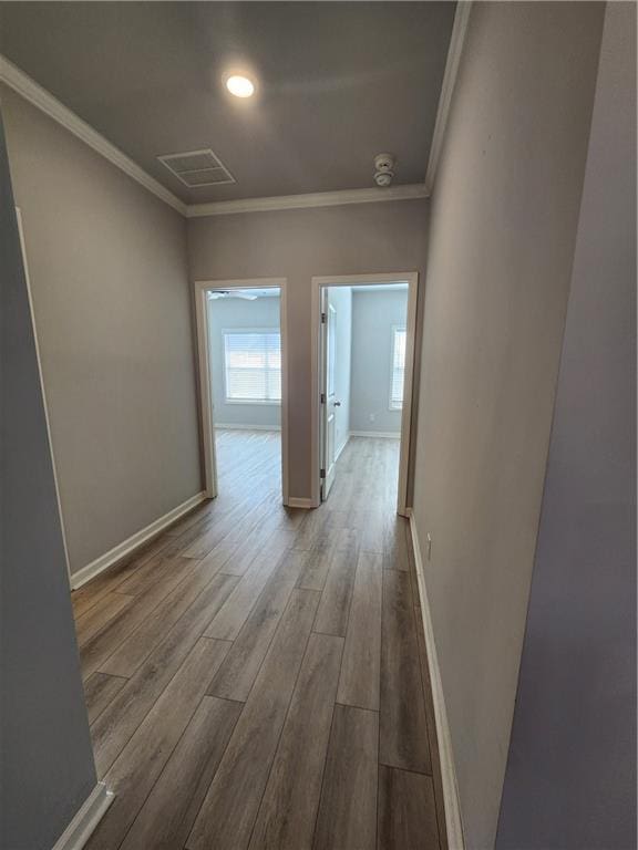 hall featuring baseboards, ornamental molding, and wood finished floors