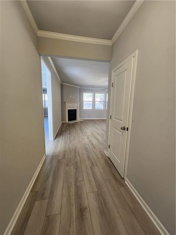 hallway with ornamental molding, wood finished floors, and baseboards