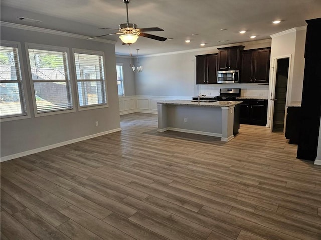 kitchen with open floor plan, ornamental molding, stainless steel microwave, and wood finished floors