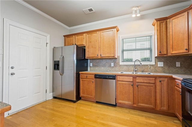 kitchen with light wood finished floors, visible vents, appliances with stainless steel finishes, crown molding, and a sink