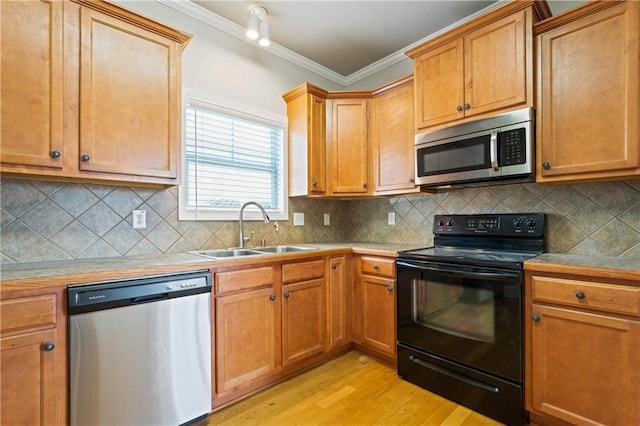 kitchen with light wood finished floors, decorative backsplash, appliances with stainless steel finishes, crown molding, and a sink