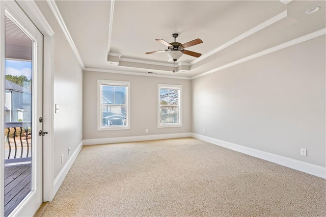 unfurnished room featuring baseboards, light colored carpet, ceiling fan, ornamental molding, and a tray ceiling