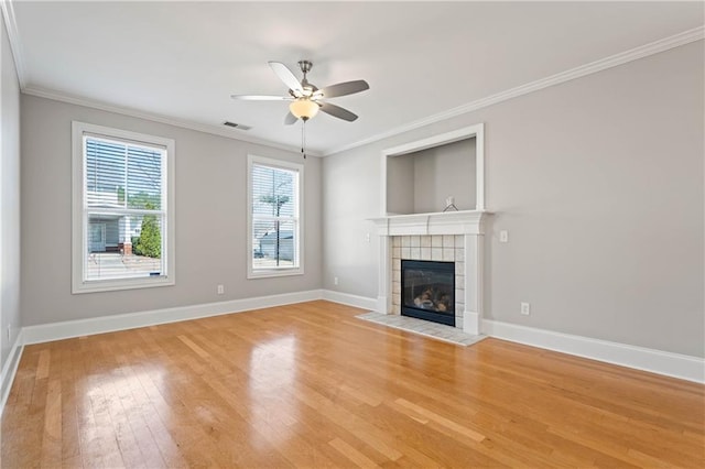 unfurnished living room with light wood-type flooring, visible vents, crown molding, and a tile fireplace