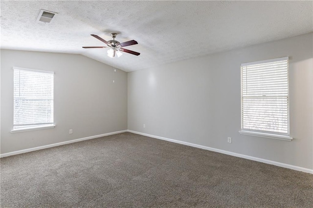 carpeted empty room featuring a textured ceiling, ceiling fan, plenty of natural light, and lofted ceiling