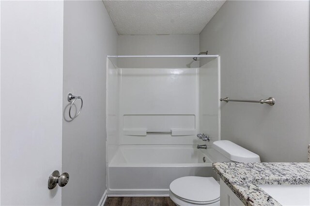 full bathroom with vanity, bathing tub / shower combination, hardwood / wood-style flooring, toilet, and a textured ceiling