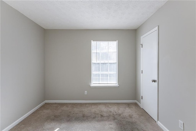 spare room with light colored carpet and a textured ceiling