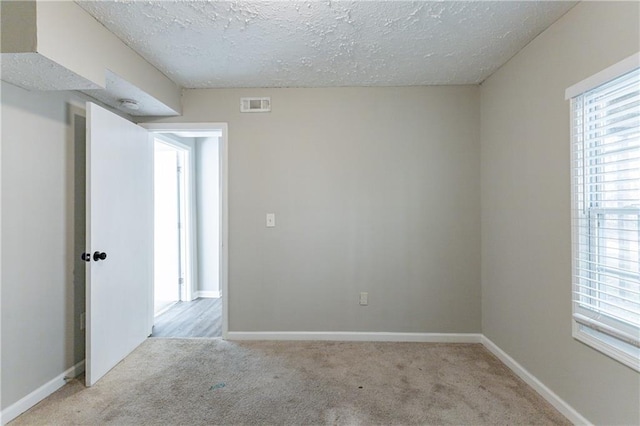 carpeted spare room with a textured ceiling