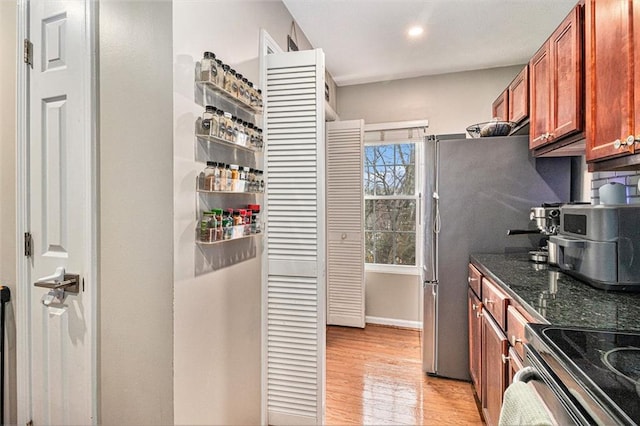 kitchen with light hardwood / wood-style flooring, stainless steel range with electric cooktop, and dark stone counters