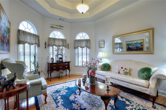 living room with a raised ceiling, plenty of natural light, crown molding, and hardwood / wood-style flooring