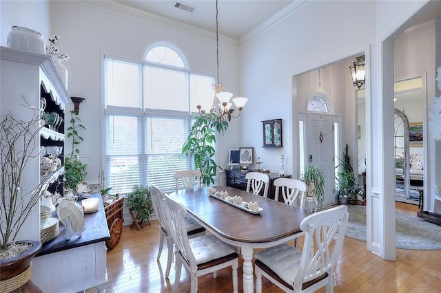 dining space featuring crown molding, a healthy amount of sunlight, an inviting chandelier, and light hardwood / wood-style floors