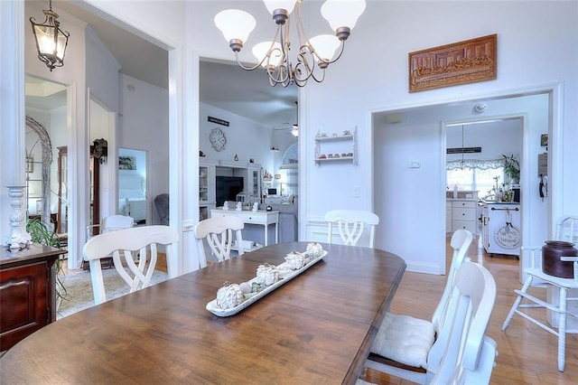 dining space featuring light wood-type flooring and ceiling fan with notable chandelier