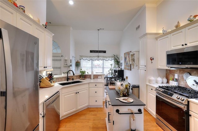 kitchen featuring decorative backsplash, sink, light hardwood / wood-style flooring, hanging light fixtures, and stainless steel appliances