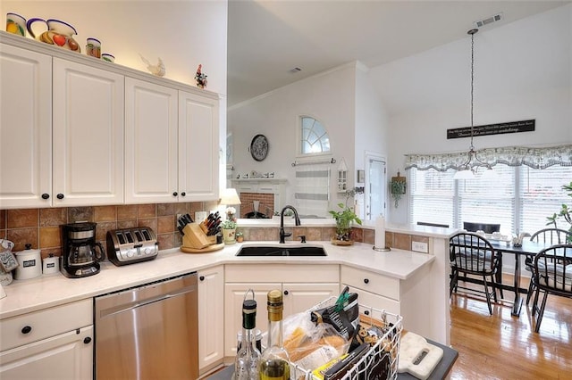 kitchen featuring decorative light fixtures, sink, white cabinetry, and stainless steel dishwasher