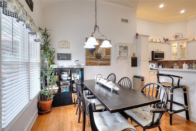 dining area featuring crown molding, a notable chandelier, and light wood-type flooring